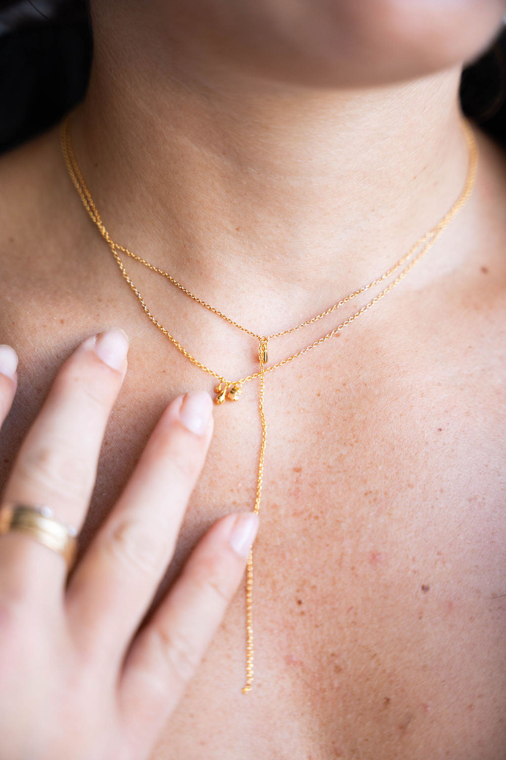 Close-up of a person wearing a delicate gold necklaces