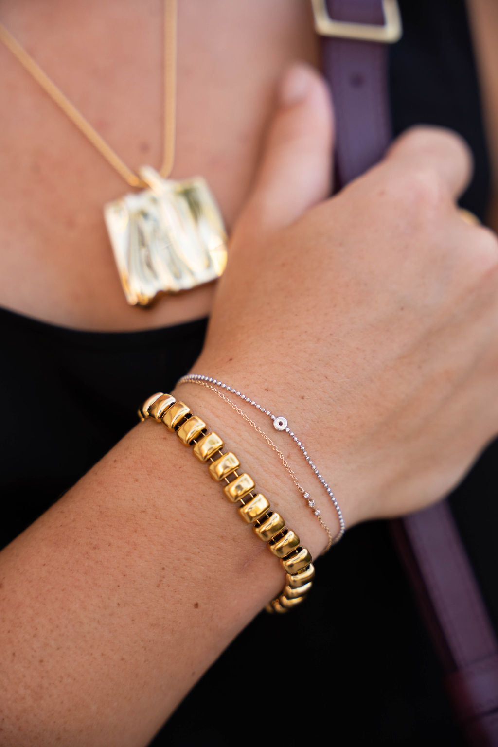 Close-up of a person's wrist wearing gold bracelets with a blurred background