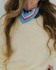 Person wearing a colorful layered scarf with a neutral background