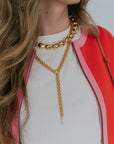 Person wearing a gold chain necklace with a red jacket and white shirt.