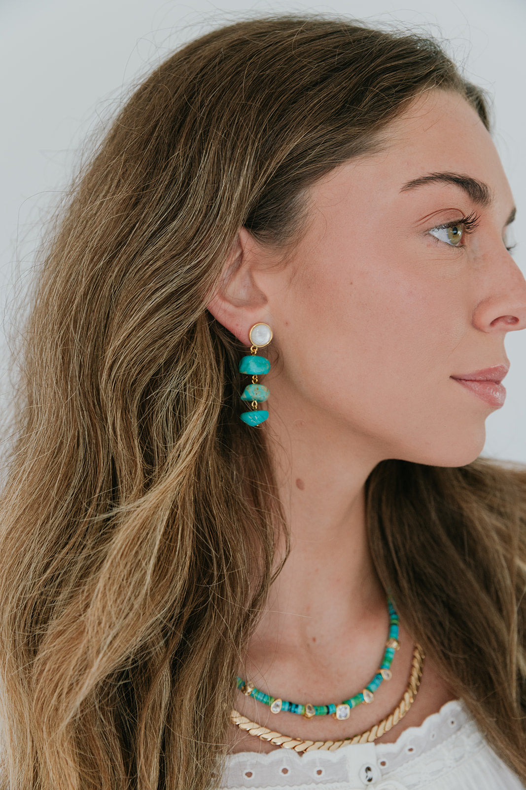 Woman wearing turquoise earrings, necklace and Paloma Chain - L with a white background