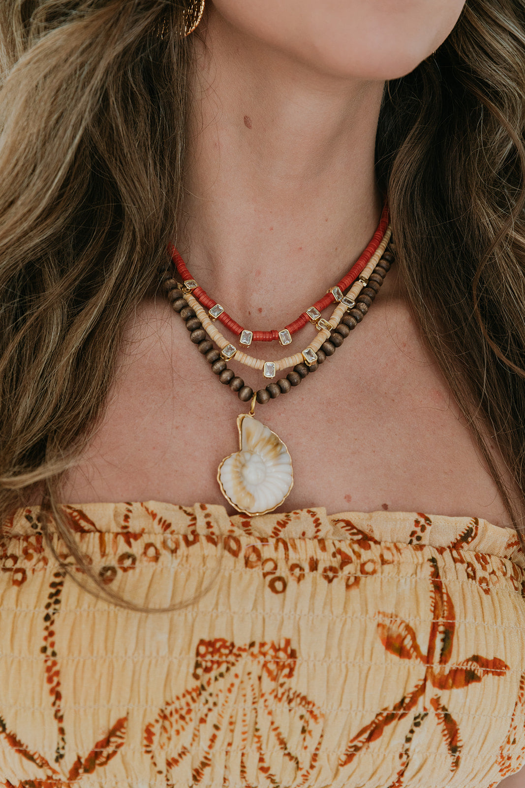 Close-up of a person wearing a necklace with a shell pendant