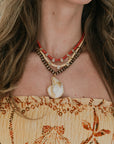 Close-up of a person wearing a necklace with a shell pendant