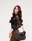 Woman wearing The Love Language Long Sleeve Top, holding a leopard print handbag against a white background, side view