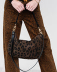 Person wearing leopard print pants holding Moyen Messenger in Cocoa Pablo Cat