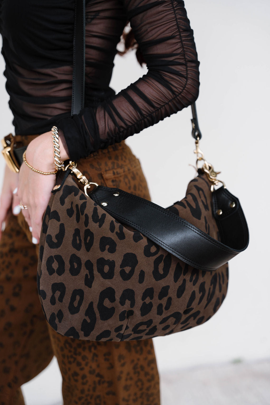 Person holding a leopard print handbag with a plain background