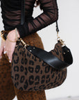 Person holding a leopard print handbag with a plain background