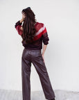 Person wearing a striped sweater and leather pants against a white background, back