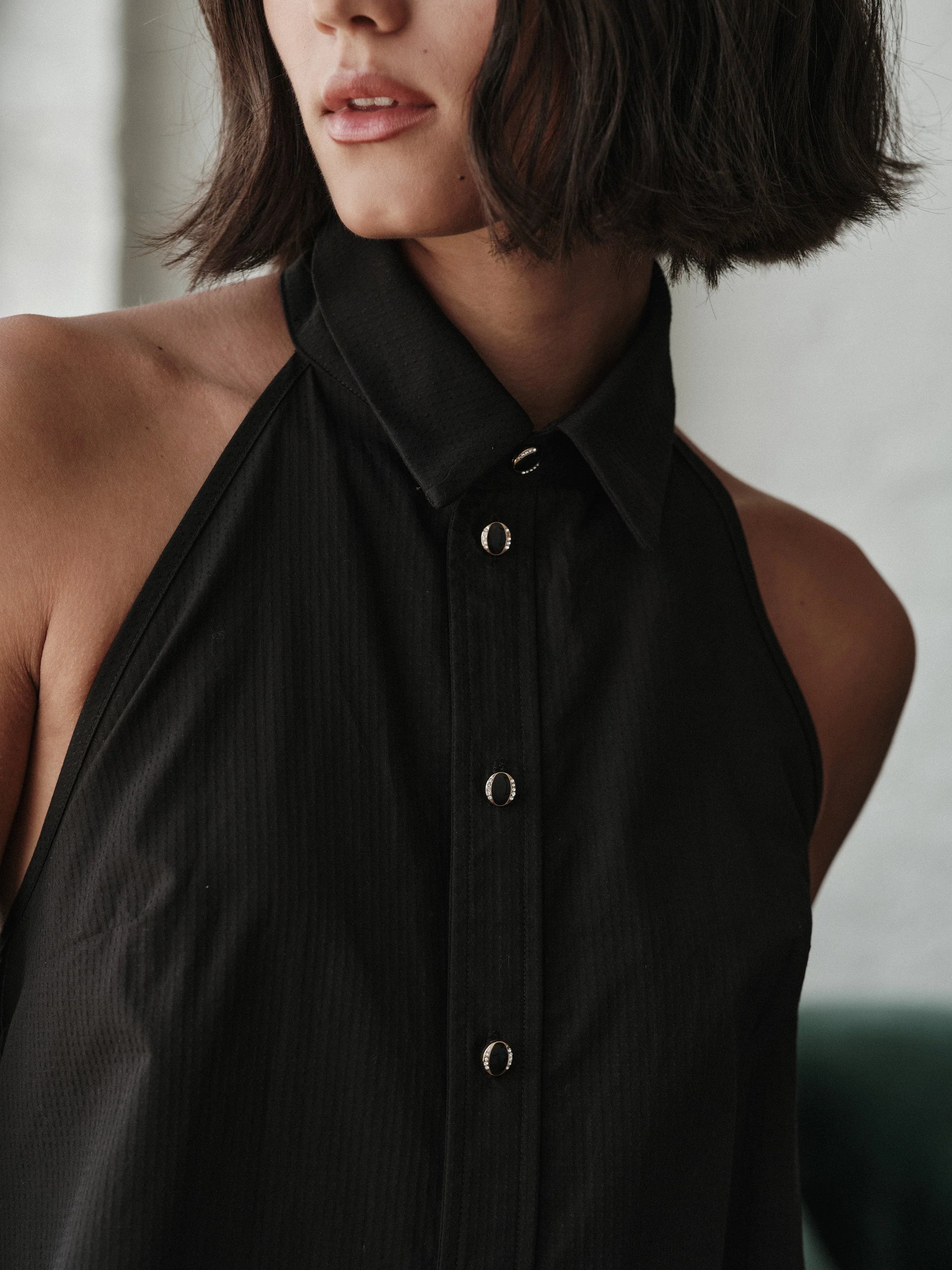 Person wearing a black halter neck top with a blurred background