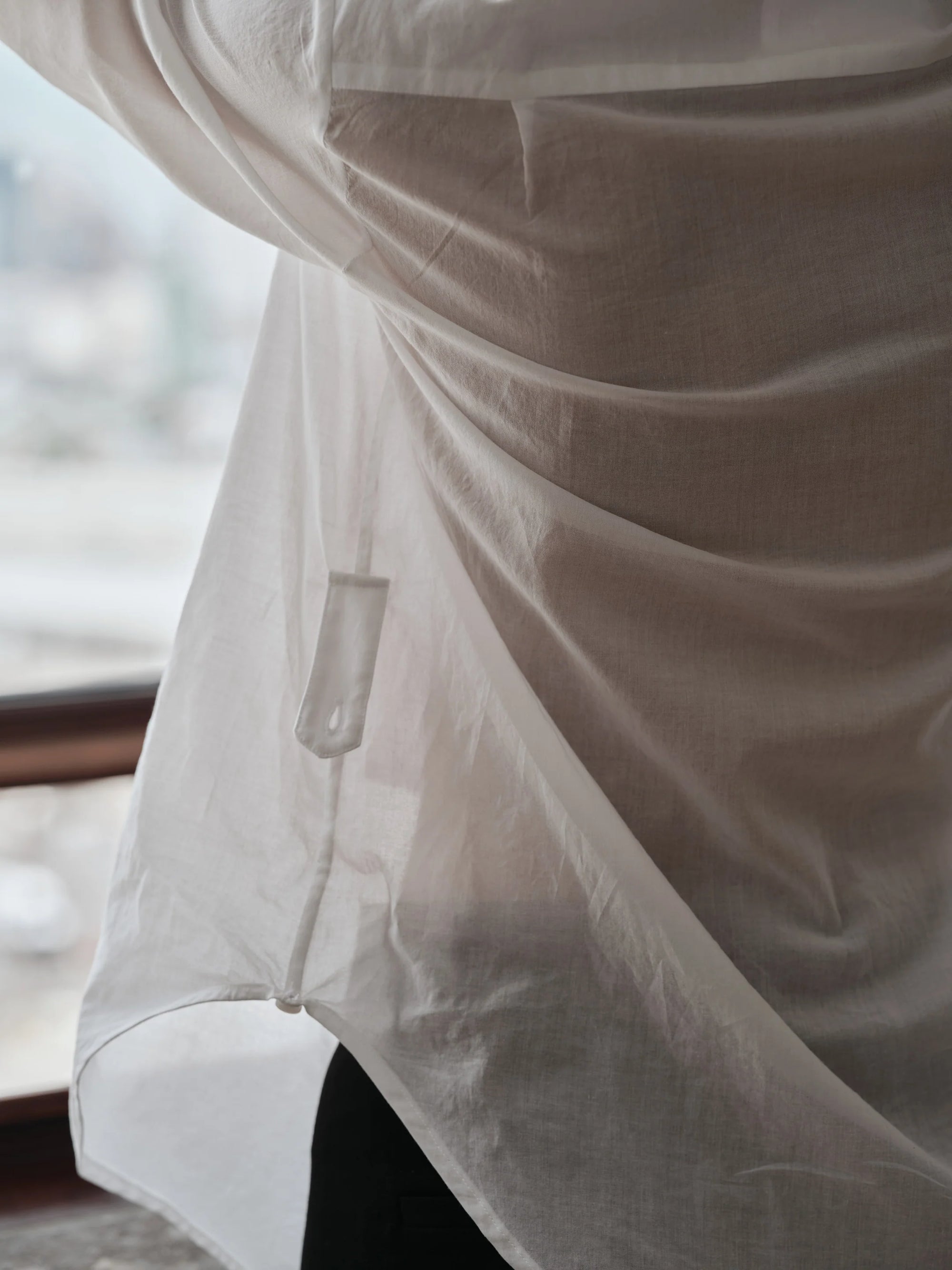 Close-up of a white shirt with a button, blurred background