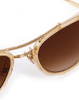 Gold-framed sunglasses with brown lenses on a white background