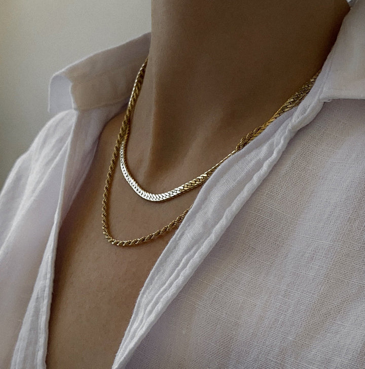 Gold chain necklace worn by a person with a white shirt