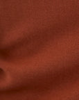 A close-up of a rust-colored knit fabric texture with soft folds and horizontal ribbing.