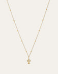 A delicate gold necklace with a small mushroom-shaped pendant, displayed against a solid off-white background.