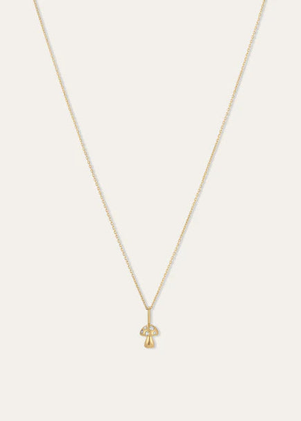 A delicate gold chain necklace with a small mushroom-shaped pendant, displayed against a solid off-white background.