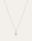 A delicate gold chain necklace with a small mushroom-shaped pendant, displayed against a solid off-white background.