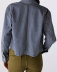 Person wearing a blue and white striped shirt with green pants on a white background