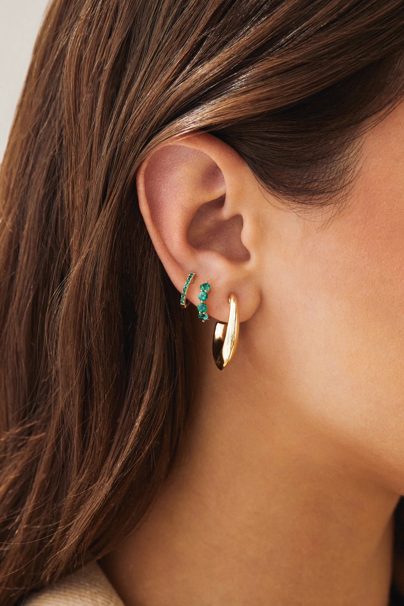 Single Reversible Diamond And Emerald Mini Huggie Earring with emerald side out, in third hole
