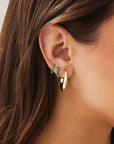 Single Reversible Diamond And Emerald Mini Huggie Earring with emerald side out, in third hole
