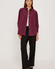 Woman wearing a burgundy striped shirt and black pants on a white background front view