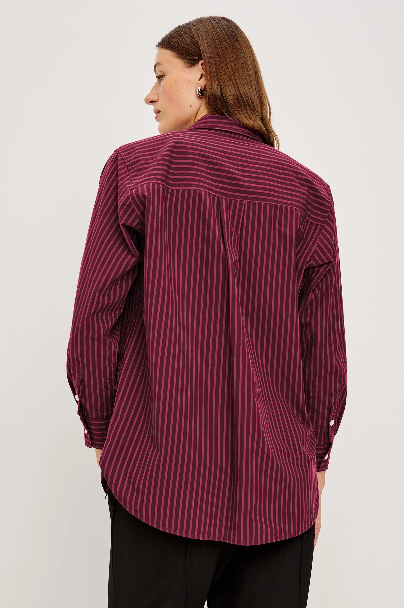 Person wearing a maroon striped shirt on a white background back view