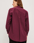 Person wearing a maroon striped shirt on a white background back view