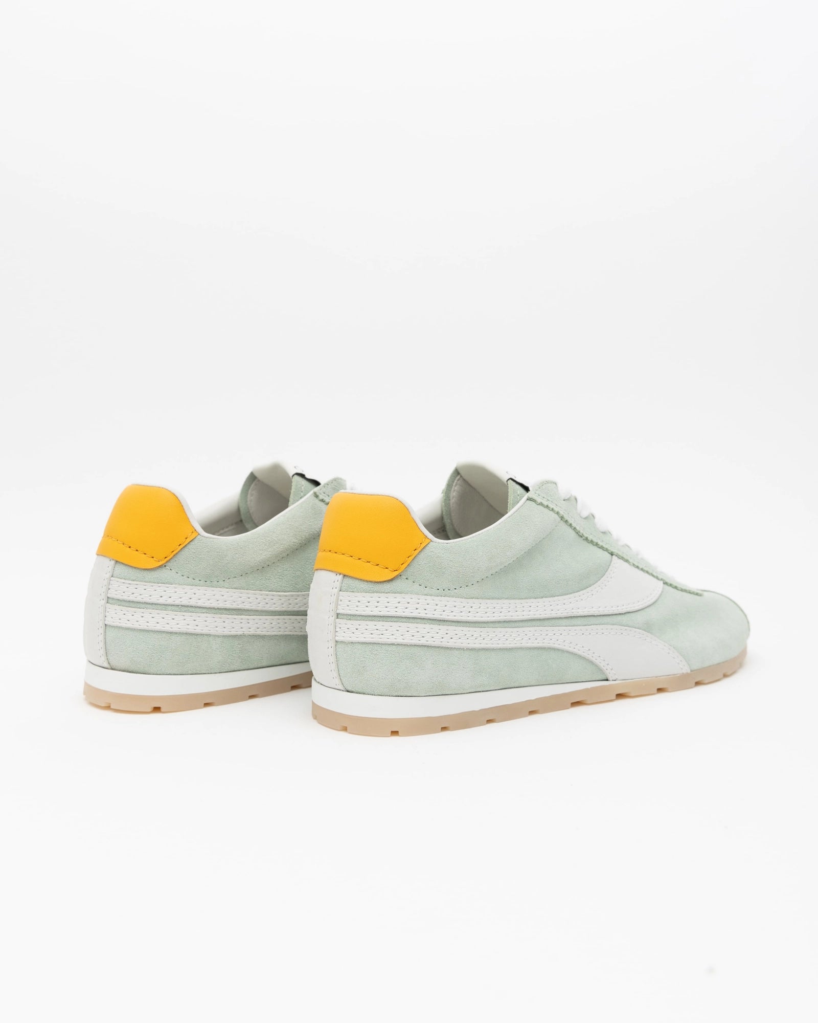 Light green sneakers with yellow accents on a white background, back view