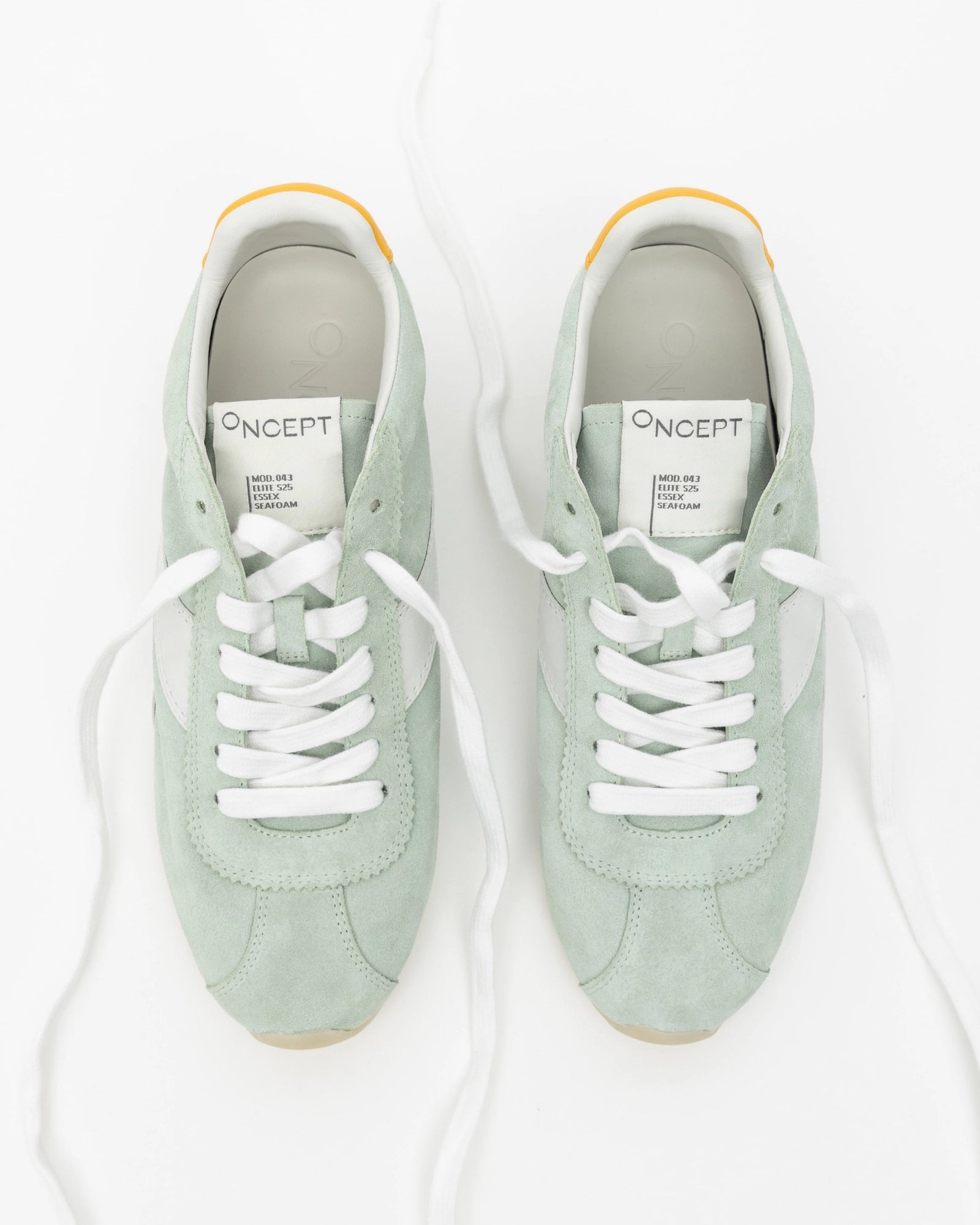 Pair of light green sneakers with white laces on a white background
