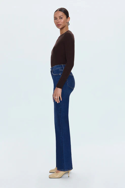 Woman wearing blue jeans and a brown top on a white background