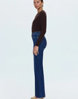 Woman wearing blue jeans and a brown top on a white background