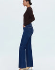 Woman wearing blue jeans and a brown top on a white background