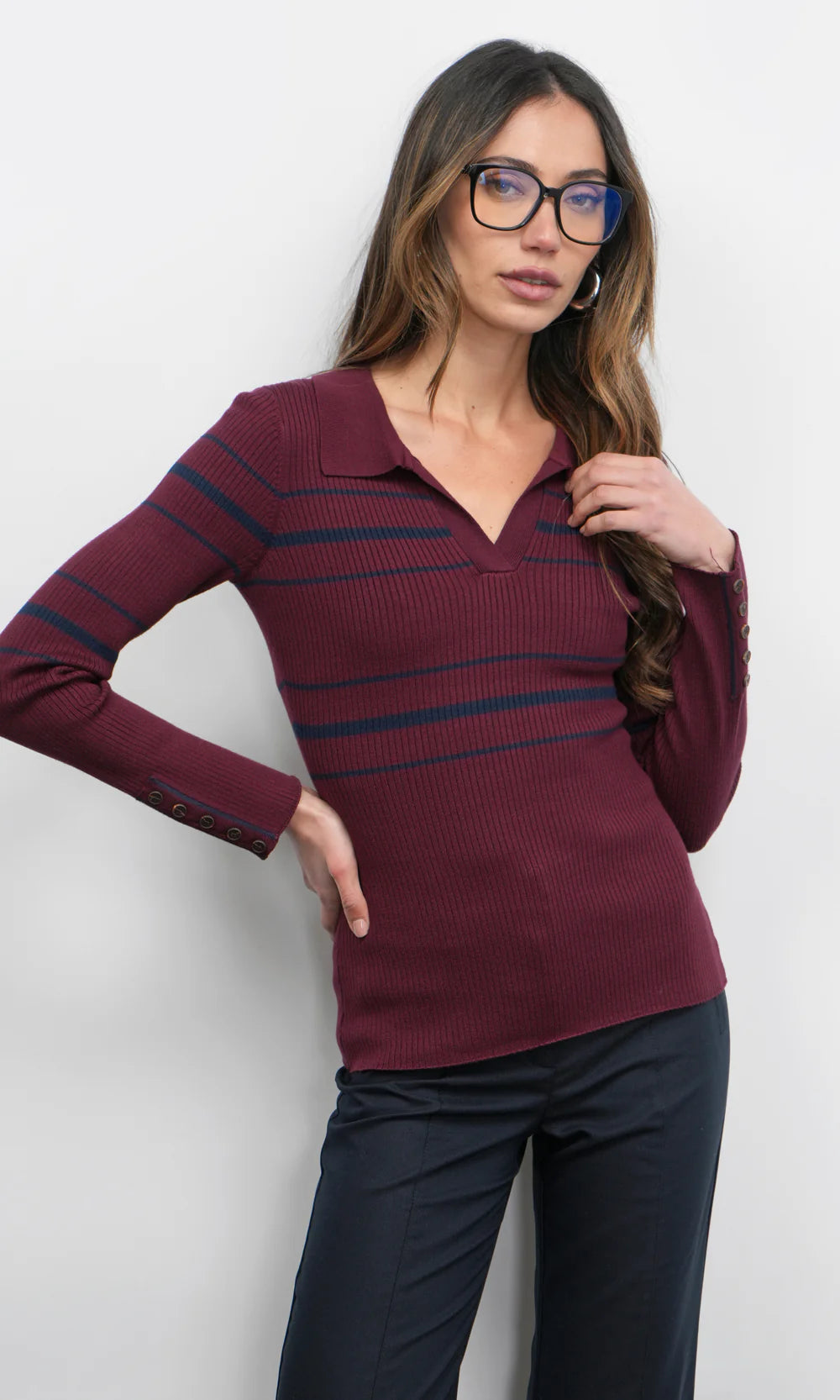 Woman wearing a burgundy sweater with blue stripes against a white background