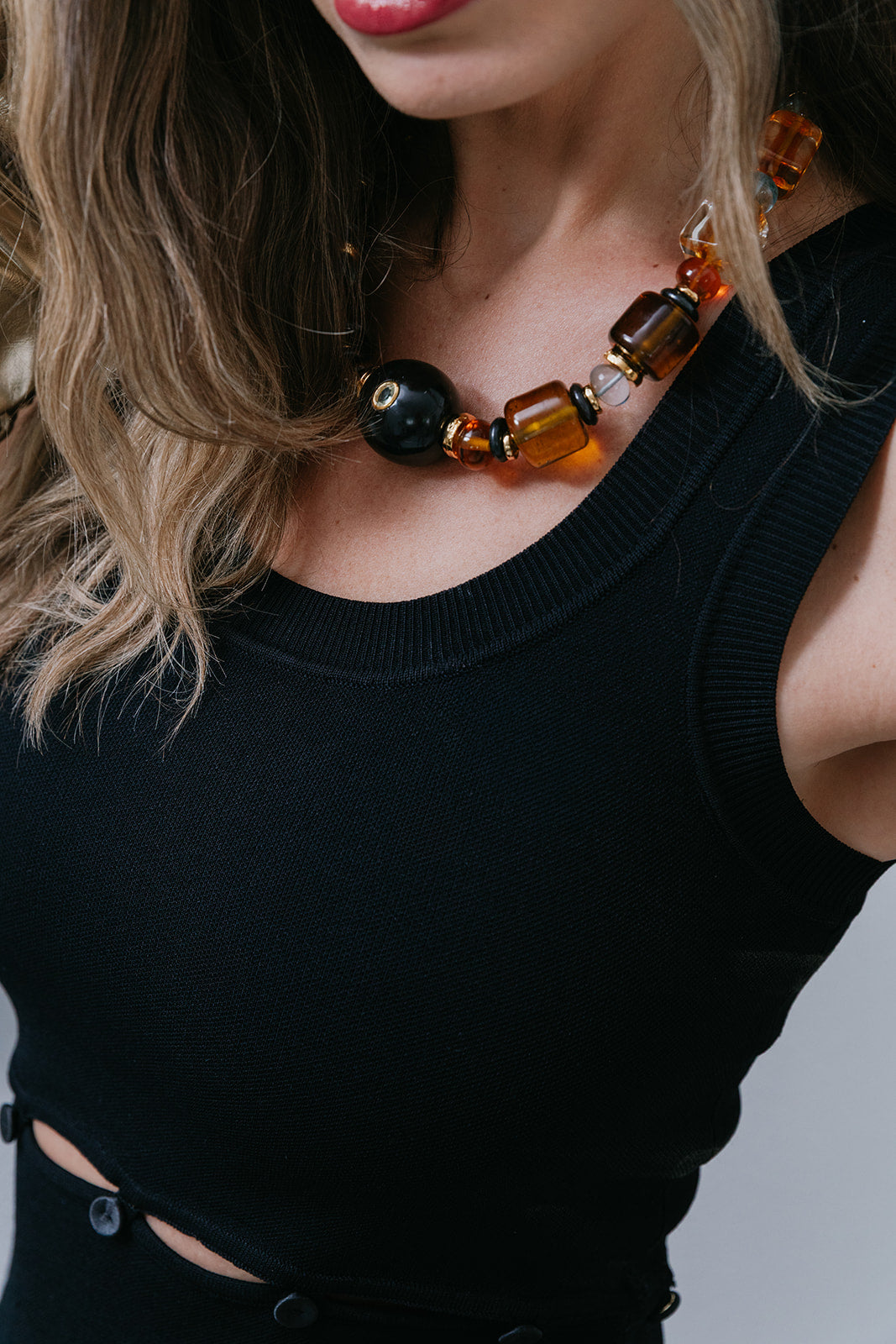 Close-up of a person wearing a black top and a colorful beaded necklace.