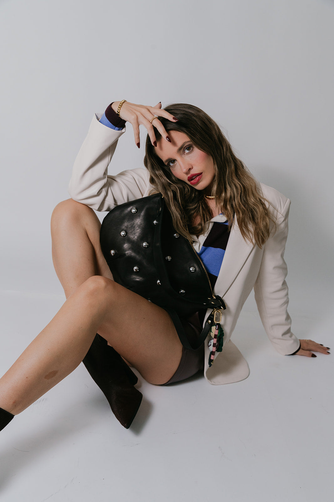 Woman posing with a black leather bag on a white background
