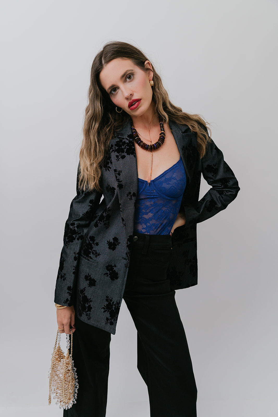 Woman wearing a black floral blazer over a blue top with a plain background