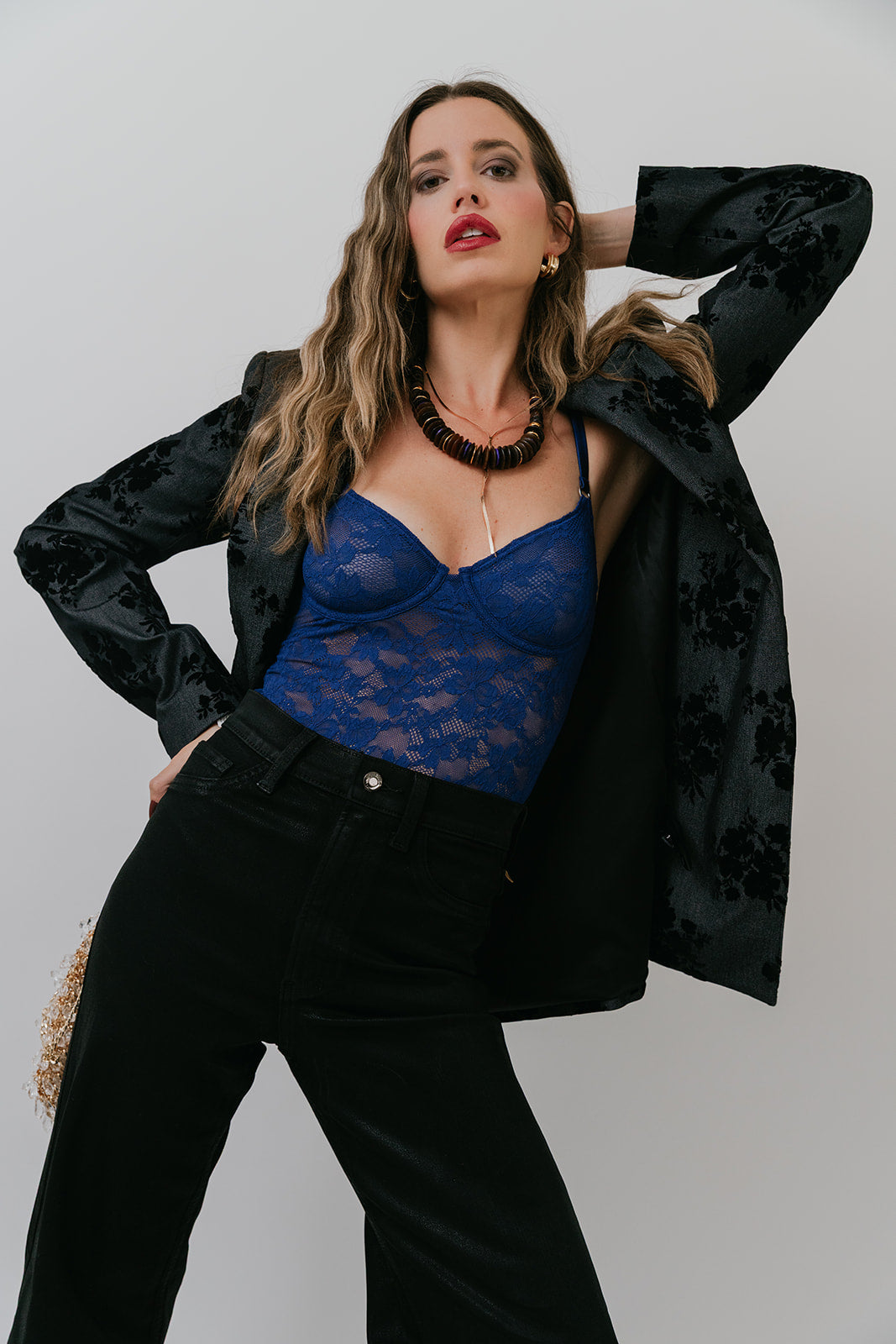 Woman wearing a black jacket and blue top against a plain background