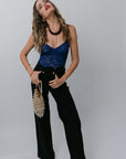 Woman wearing a blue top and black pants against a gray background
