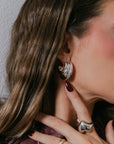 Close-up of a woman wearing silver earrings and rings with a neutral background