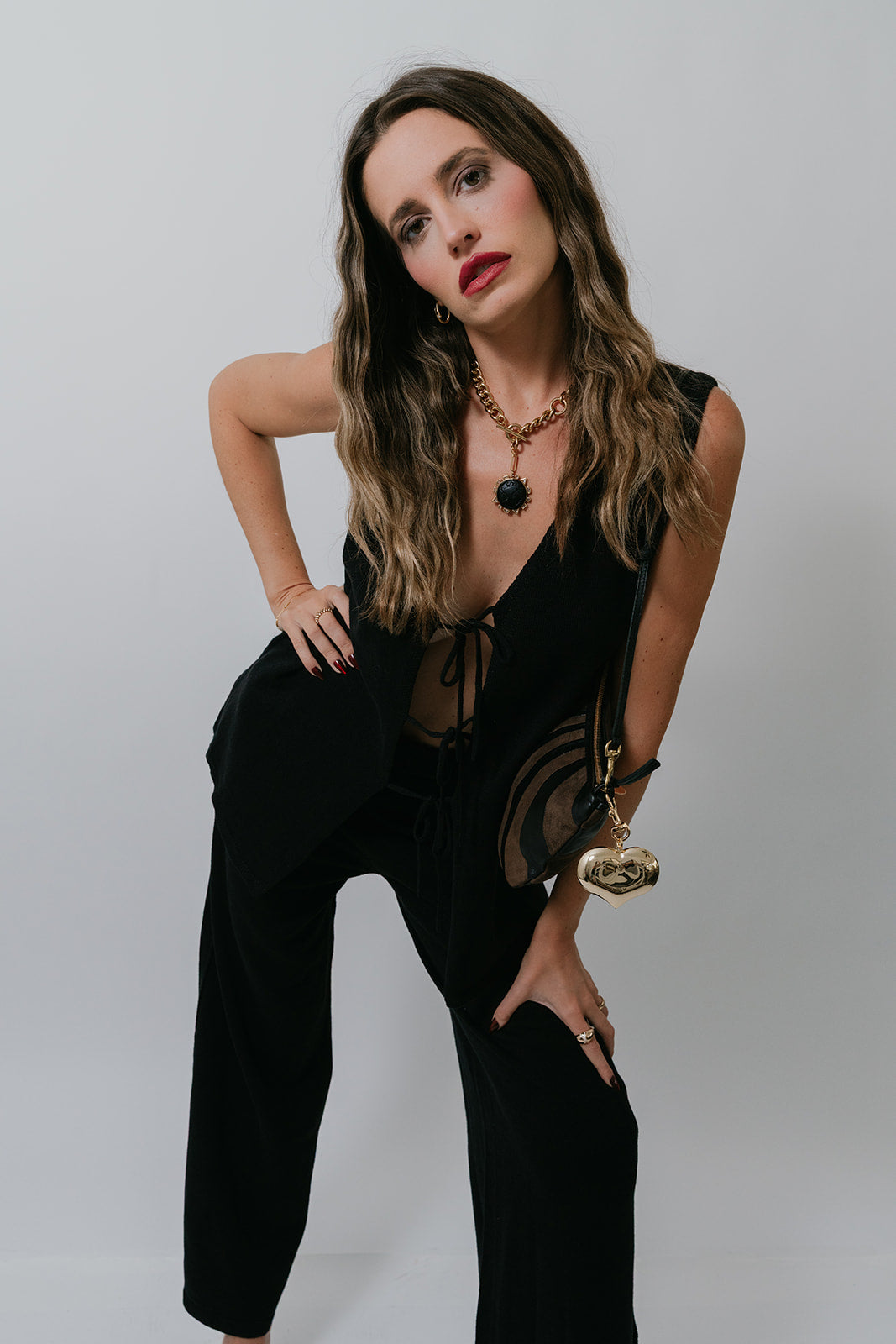 Woman wearing a black outfit leaning forward against a plain background