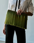 model holding an oversized green tassel clutch while wearing a black and white top with black bottoms 