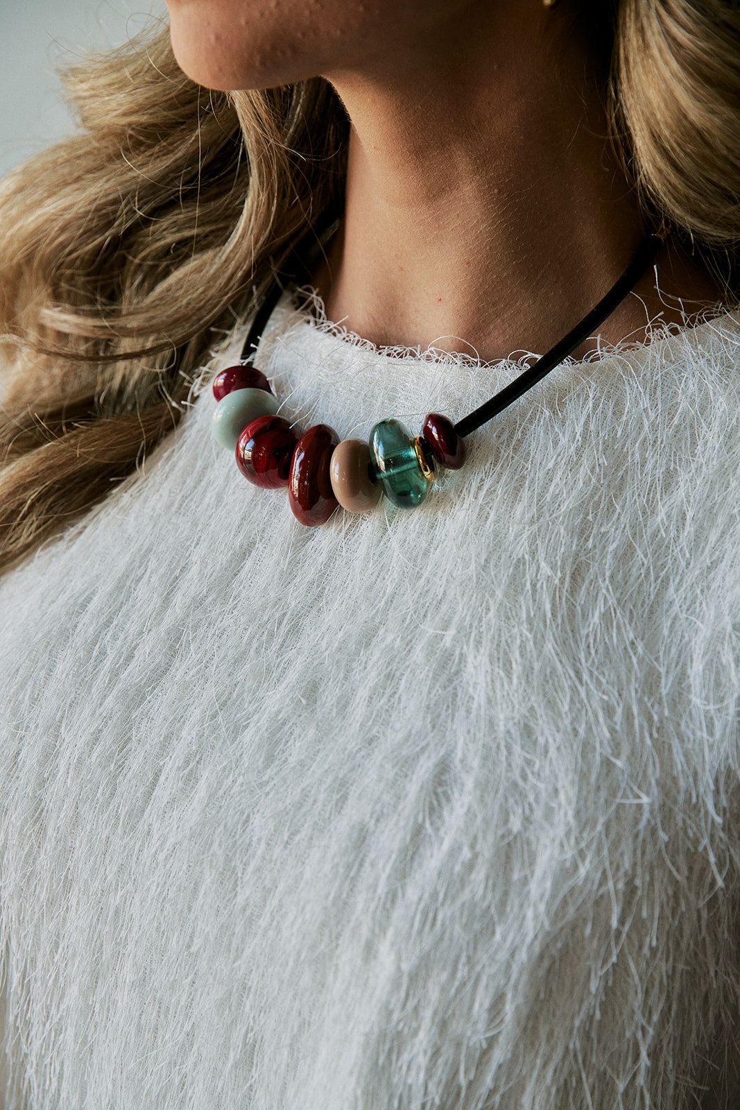 beaded piedra necklace on a model wearing a white tassel shirt 