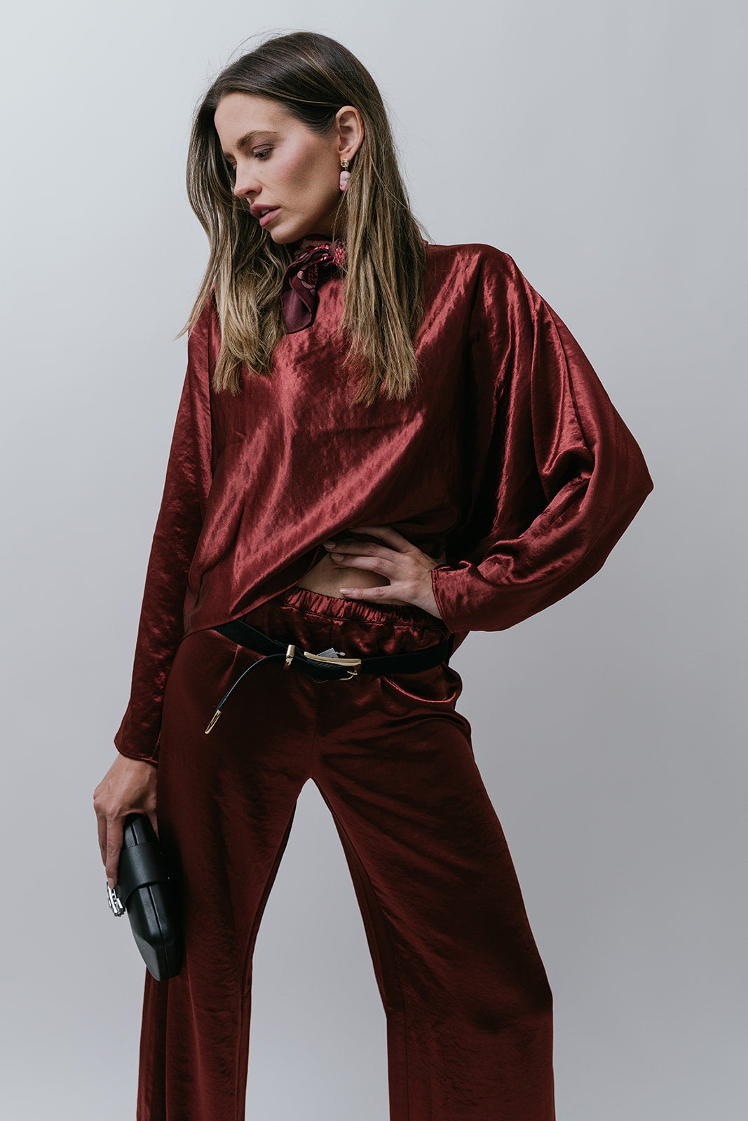 Woman wearing a burgundy silky outfit against a plain background