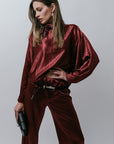 Woman wearing a burgundy silky outfit against a plain background
