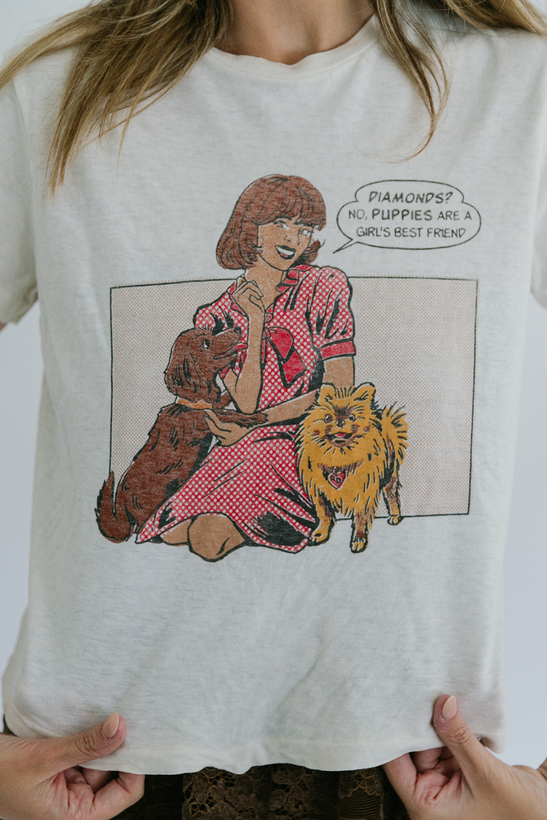 T-shirt with a graphic of a woman holding two dogs and a speech bubble.