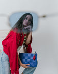 Woman holding a blue checkered bag with red lips fob against a white background
