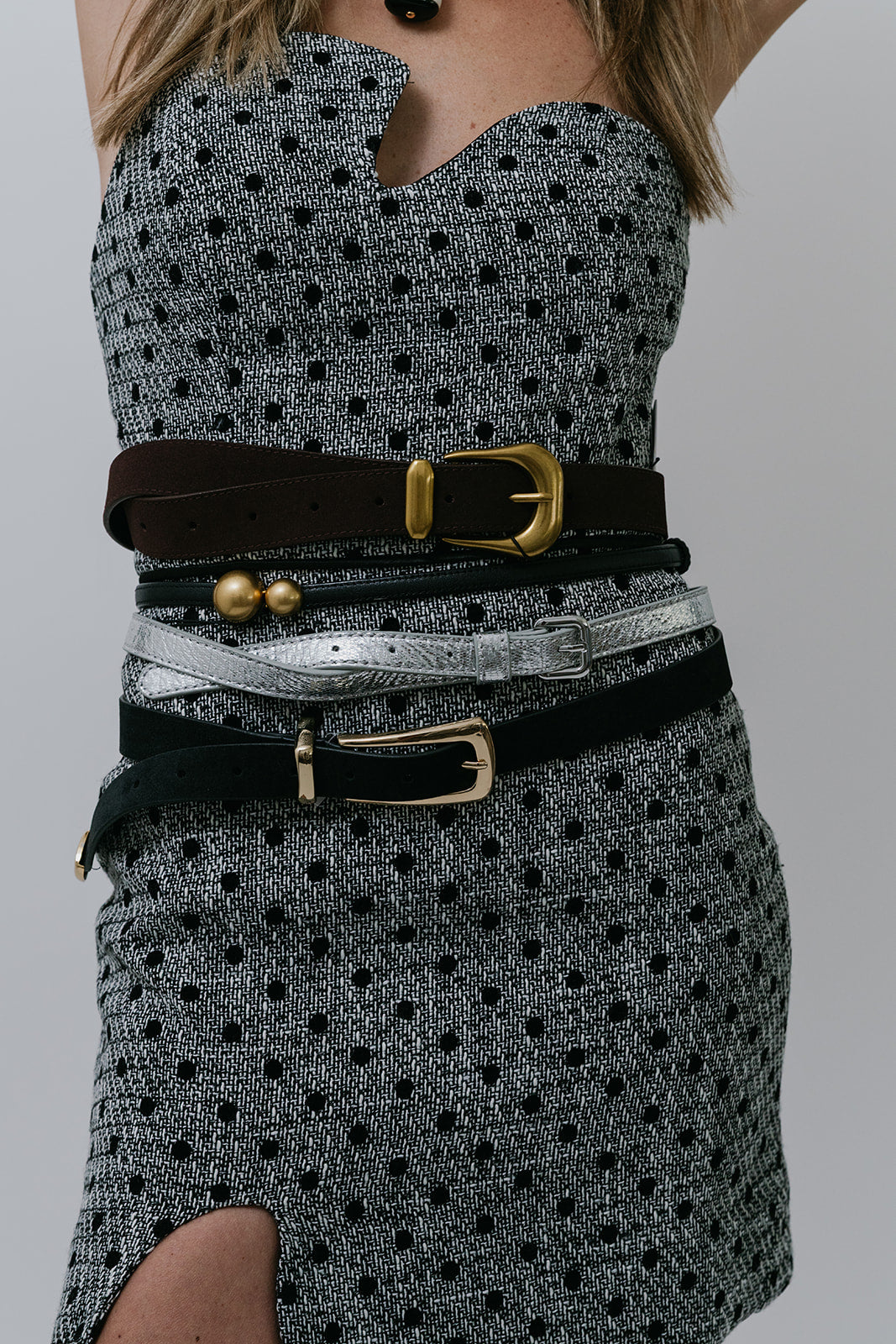 Model wearing 5 belts on polka dot dress