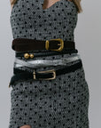Model wearing 5 belts on polka dot dress