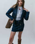 Woman wearing a denim outfit with leopard print boots and clutch against a plain background