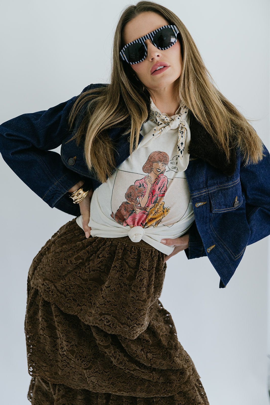 Woman wearing a denim jacket, white graphic t-shirt, and denim jacket against a white background