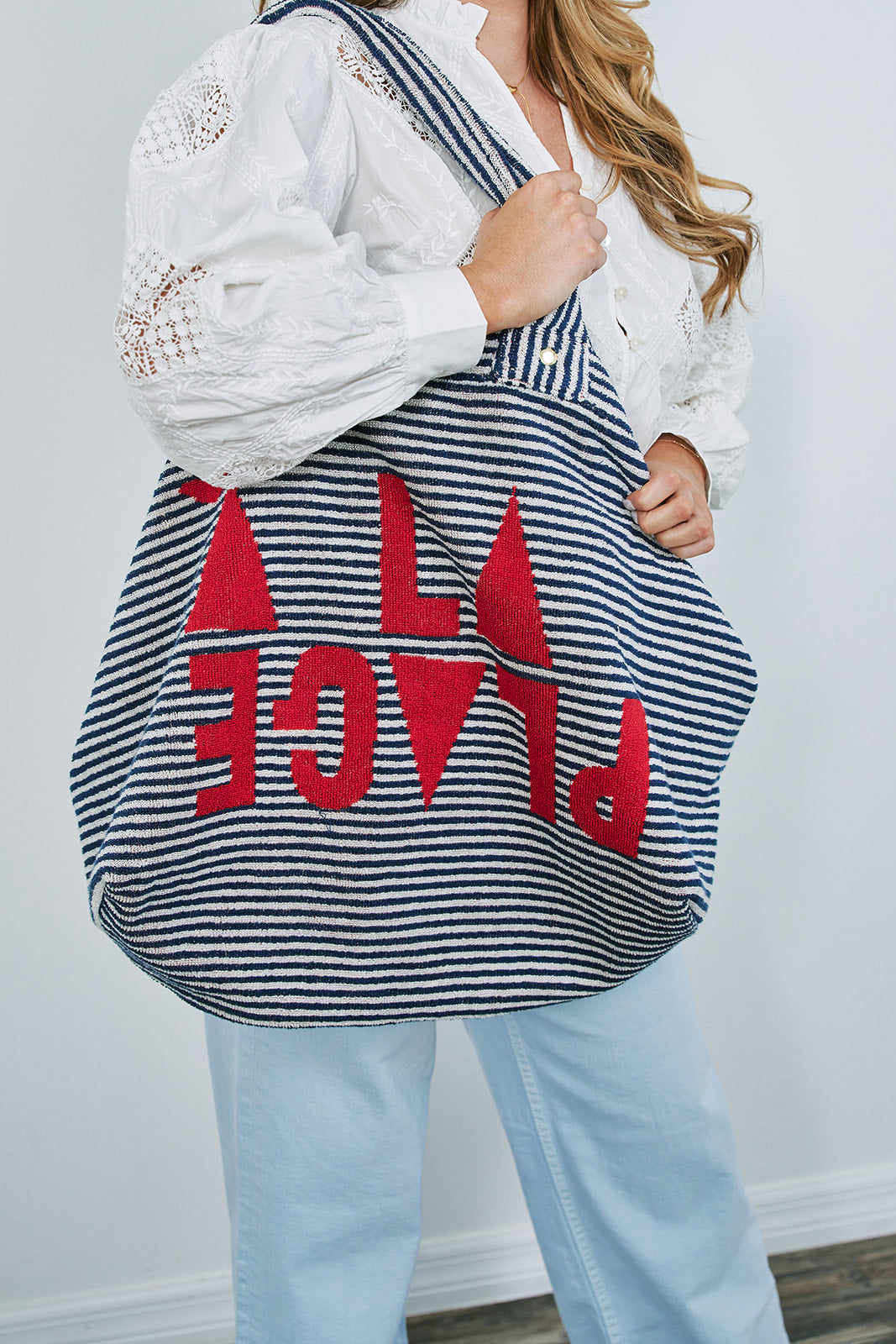 Person holding a striped bag with red letters against a white background
